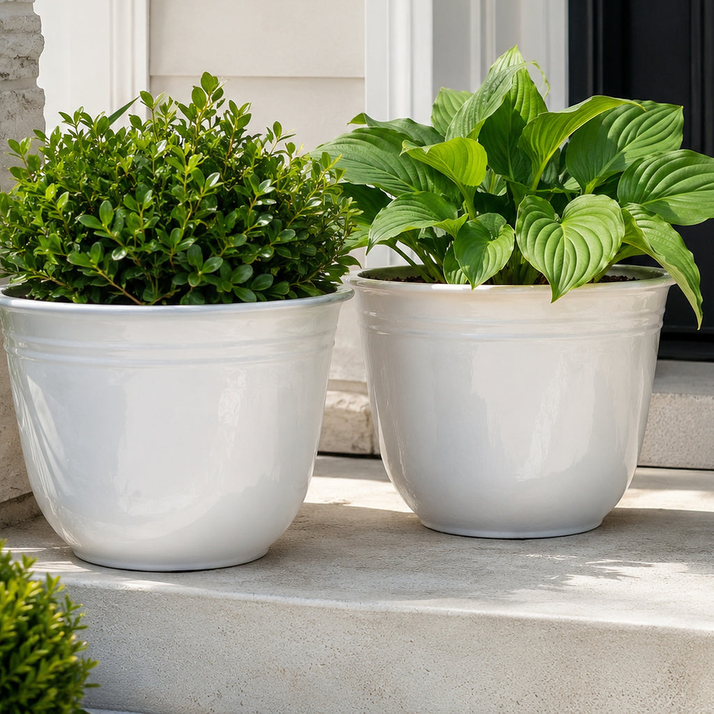Illustrative close lifestyle view of two white planters with greenery on a porch